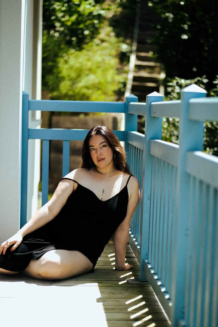 Woman seated at a balcony wearing a black dress.