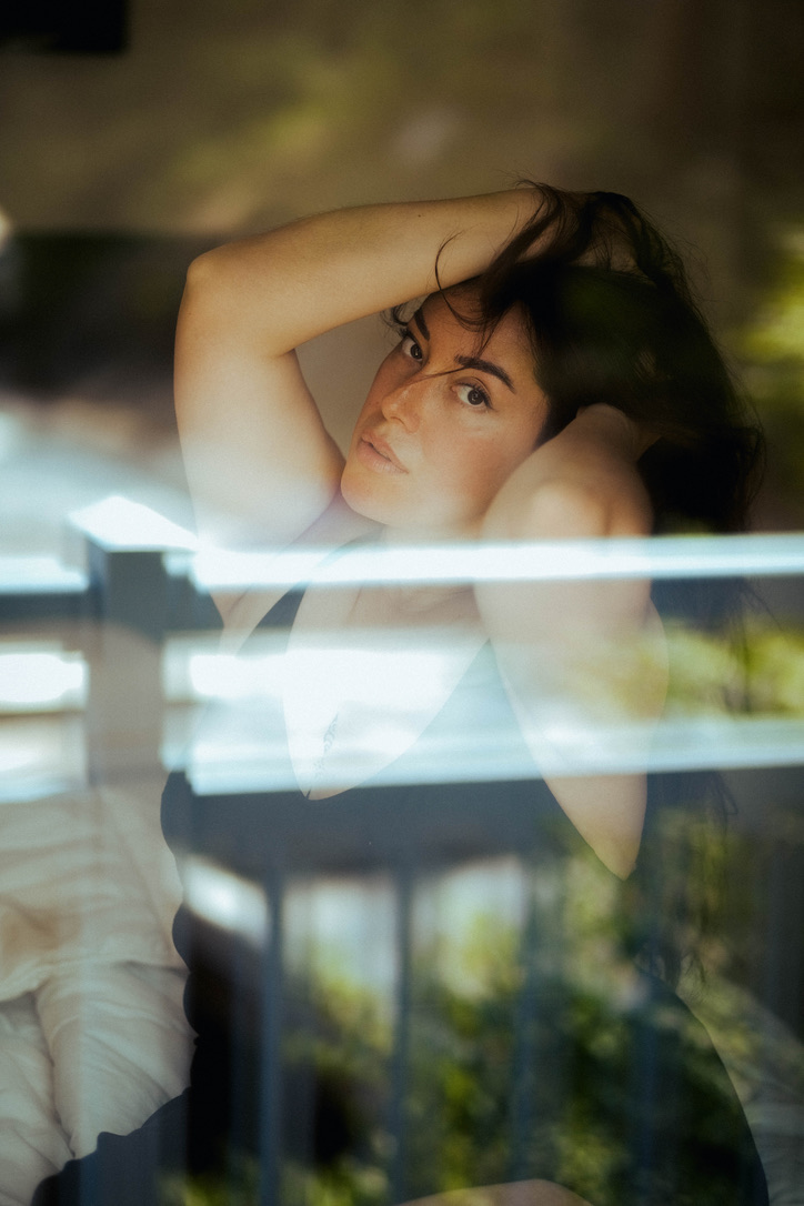 Woman holding her hair seen through the window.