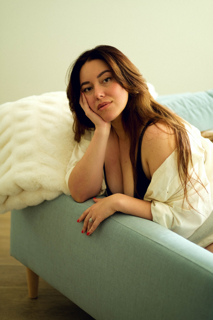 Woman leaning on a sofa her head resting on her hand.